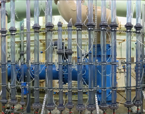 Pilot testing columns: rows of tall clear pipes and blue piping inside a treatment test room.